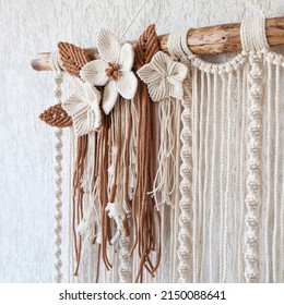 Handmade macrame wallhanging. 100% cotton wall decoration with wooden stick hanging on a white wall.   Macrame braiding and cotton threads. Female hobby.  ECO friendly modern concept in the interior