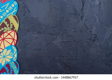 Handmade magnets in the shape of Easter eggs on a dark gray concrete background, Ukrainian traditional symbols, copy space, holiday card