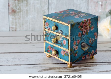 A handmade mini chest of three drawers decoupaged with blue floral vintage paper and gold leaf