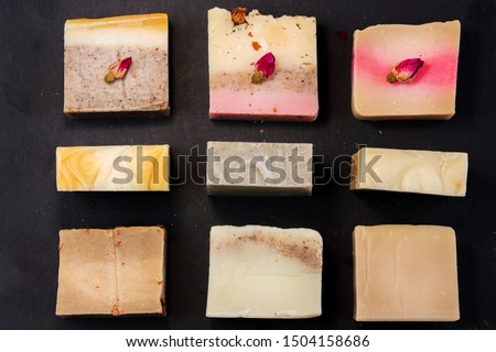 handmade multicolored soap with herbs and rosebuds on a black background with a space for text. Spa soap for face and body treatments flat lay instagram  style
