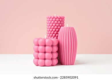 Handmade olive wax different forms pink color candle on a duotone pastel pink and white background. Sustainability vegan candle, natural materials. Minimalistic, modern photo. Copy space. Horizontal.