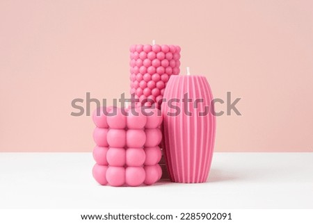 Handmade olive wax different forms pink color candle on a duotone pastel pink and white background. Sustainability vegan candle, natural materials. Minimalistic, modern photo. Copy space. Horizontal.