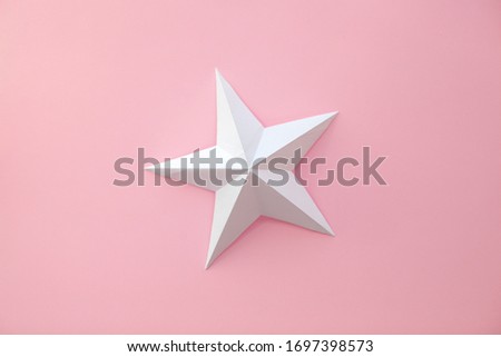 Handmade paper cutout star on pink background. 