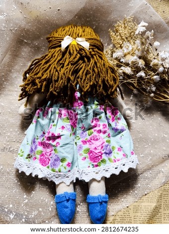 Handmade Rag Doll Back View Golden Hair Blue Shoes
Description: Back view of a handmade fabric doll with golden brown yarn hair, wearing a mint floral dress and blue felt shoes.