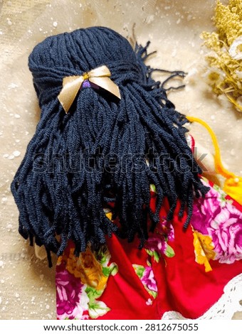 Handmade Rag Doll Back View Dark Hair Red Dress
Description: Back view of a handmade fabric doll with dark navy yarn hair tied with a gold ribbon bow, wearing a red floral dress.