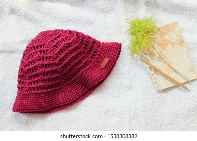 Handmade Red Crochet Hat On White Table.