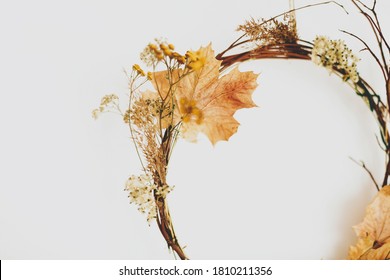 Handmade rustic autumn wreath on white wall. Rural seasonal wreath made of autumn leaves, twigs and flowers. Hello Autumn and Happy Thanksgiving decor, celebrating at home