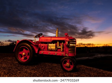 Handmade scale model of a red tractor with a morning sky in the background.