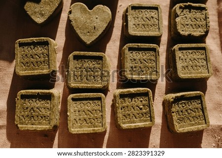 Handmade shampoo and soap solid bars arranged on pink fabric with warm sunlight, stamped details and heart shapes creating rustic natural care product display, with handmade, soap, shampoo, solid