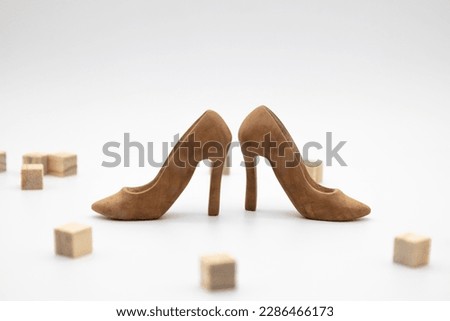 Handmade shoes for use in female concept. A beautiful high-heeled wooden shoes stand between wooden cubes against white background. 