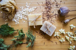 手工制作的温泉肥皂棒与天然成分。 有机肥皂制作，皮肤护理。 干草药，燕麦，玫瑰花在木制复古背景。 水疗护理。