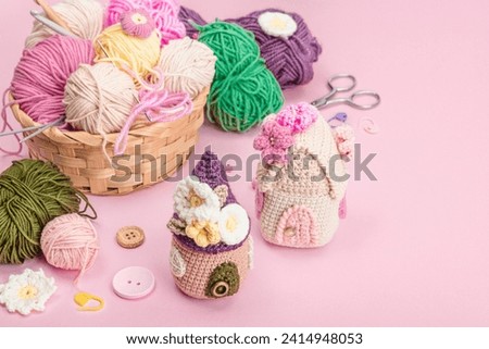 Handmade spring decor concept. Creative crocheting, house figurines, traditional flowers and stuff. Festive greeting card, gentle pastel pink background, copy space