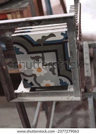 Handmade stylish designed geometric ceramic tiles with colorful ornaments placed on metal framed construction of stencil in workshop