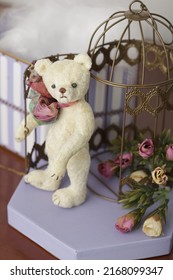 Handmade Teddy Bear With Bow From Vintage Plush Fabric, Brings Nostalgic Childhood Memories. Toy Standing Neat Box And Bird Cage Decorated With Flowers. Postcard Image. Handcraft Advertisement.