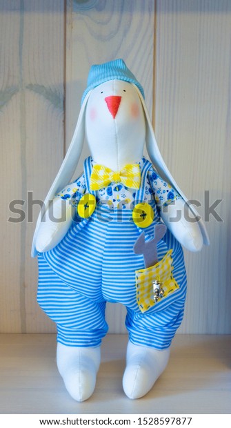 Handmade toy bunny boy in blue overalls and a\
wrench in his pocket