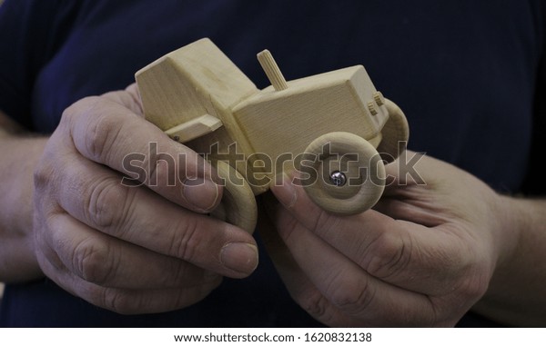 A handmade toy car\
held by its creator