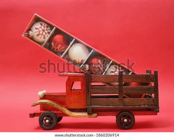 Handmade toy truck on\
red paper background. round christmas toys in box. happy new year\
and merry christmas.