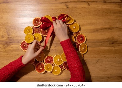 Handmade tying ribbon Christmas wreath from dried orange grapefruit slices. Festive holiday preparation craft master class of creative making decor. Hands-on activities sustainable responsible holiday - Powered by Shutterstock