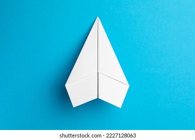 Handmade white paper plane on light blue background, top view