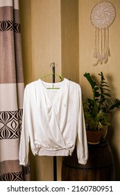 Handmade White Silk Blouse Hanging On A Hanger In The Room.