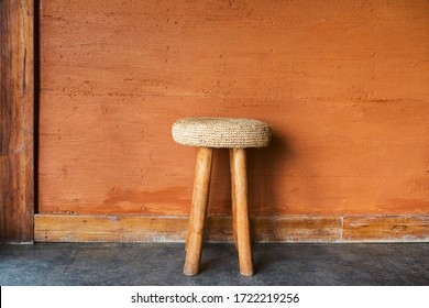 Handmade Wooden Chair With Wicker Straw Pillow On Background Of Red Terracotta Wall With Decorative Plaster. Moroccan Rustic Interior And Furniture Design.