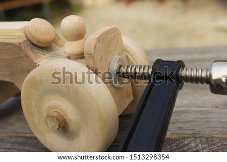Handmade wooden toy for boy. Gluing process. Clamped by clamp