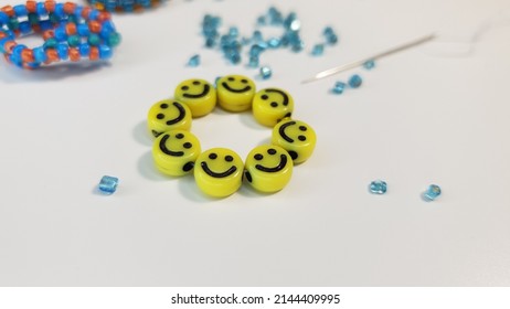 Handmade work. A ring of yellow beads with smiles. Children's creativity. Handiwork. Blue beads. Needle for embroidery.