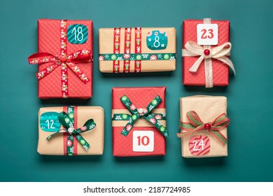 Handmade wrapped red, green gift boxes decorated with ribbons, snowflakes and numbers, Christmas decorations and decor on green table Xmas advent calendar concept Top view Flat lay Holiday card