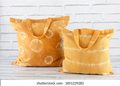 Handmade yellow tie dye cotton bags on white background. Natural fabric dyes