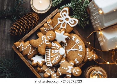 Handmade zero waste gift for Christmas or New Year. Wooden box with homemade delicious gingerbread cookies decorated with white icing. Cozy home atmosphere, fairy lights, fir tree branches - Powered by Shutterstock