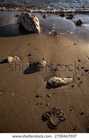 Handprint impression in the sand created using a plastic beach mold. Simple summer detail symbolizing childhood, play, and seaside memories
