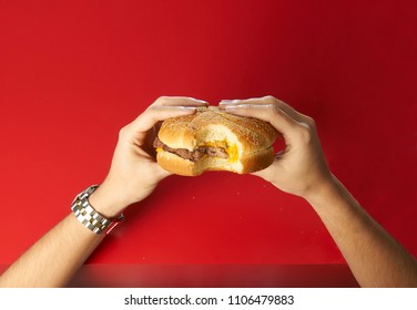 Hands About To Eat A Wendy´s Burger With A Bite On A Red Table Background