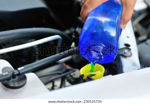 hands adding auto\
glass cleaner for car 