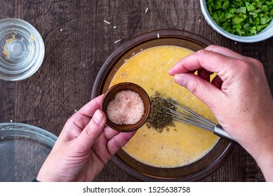 Woman’s hands adding a pinch of pink Himalayan salt to raw egg mixture in glass bowl, on a wood table
 - Powered by Shutterstock