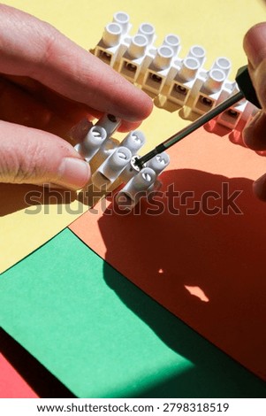Hands Adjusting Electrical Terminal Block with Screwdriver 