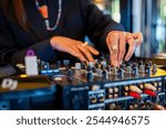 A DJ’s hands adjusting knobs on a mixer, vibrant nightlife scene with focus on music control. Perfect for themes of music, nightlife, entertainment, and DJing