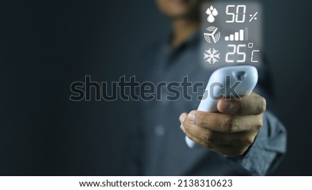 Hands are adjusting the operation factor value of the air conditioner via remote control fan speed temperature 25 degrees Celsius for energy saving in summer when electricity consumption increases.