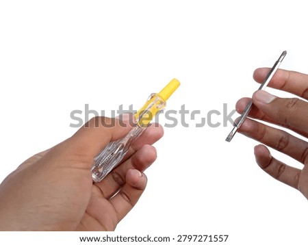 Hands adjusting a yellow test pen screwdriver with an interchangeable metal bit isolated on white background