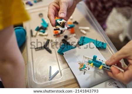 the hands of an adult assemble parts of a plastic designer according to the instructions, a children's toy, prefabricated parts for construction