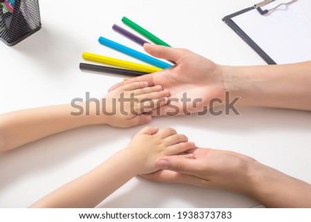 The hands of an adult are holding the baby's hands. The concept of psychological characteristics of children, the development of mental processes in children. Self-conception and psychological feature