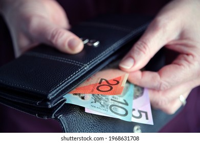 Hands Of Adult Woman Female Pulling Out Australian Money Paper Bank Note Cash Bills From A Leather Purse  Wallet.