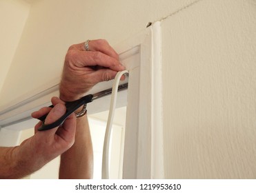 Hands Affixing Adhesive Rubber Draft Proofing To A Door Frame.