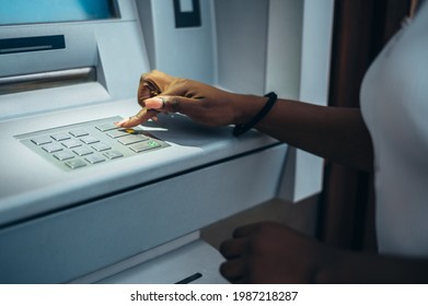 Hands of an african american woman typing pin code and withdrawing cash at the ATM