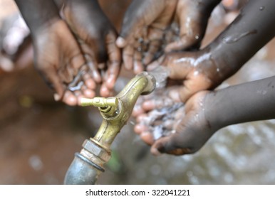 Hands Of African Children Cupped Under Tap Drinking Water Malnutrition. Hands Of African Black Boys And Girls With Water Pouring From A Tap. It Affects People And Especially Children In Africa. 