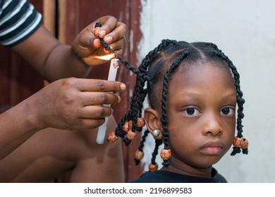 Hands Of An African Hair Stylist Or Mother Making Braided Hairstyle On The Head Of A Little Girl Child At A Saloon