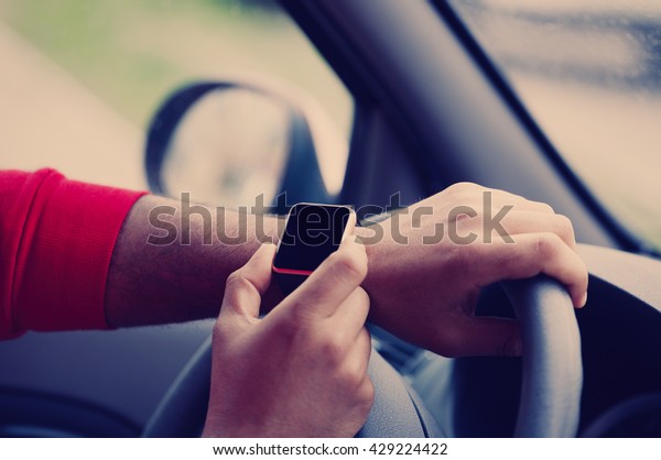 Hands of african male model\
using trendy smart wrist watches in a car. Popular new technology\
to always stay connected to internet and social media. Close up\
macro 