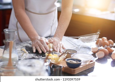 Hands Of Anonymous Woman Covered With Flour Kneading Cookie Dough On Messy Kitchen Table, Sunshine Illuminating Room