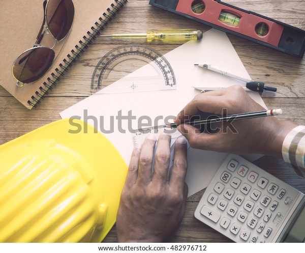 Hands of architect drawing construction plan on
wooden desk