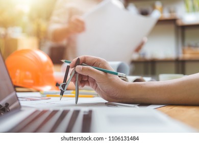 Hands of architect or engineer using drawing compass with blueprint on desk in office.Team of architects engineer discussing and check documents and business workflow.Construction concept.