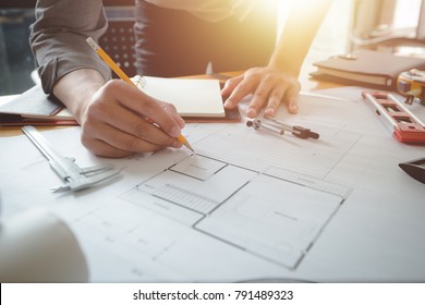 Hands of architect or engineer using pencil working with blueprint on desk in office . Engineering tools and construction concept. Architect and Business concept.Selective focus,Vintage effect.